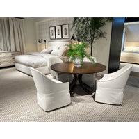 Dining room featuring white skirted chairs around wooden table.