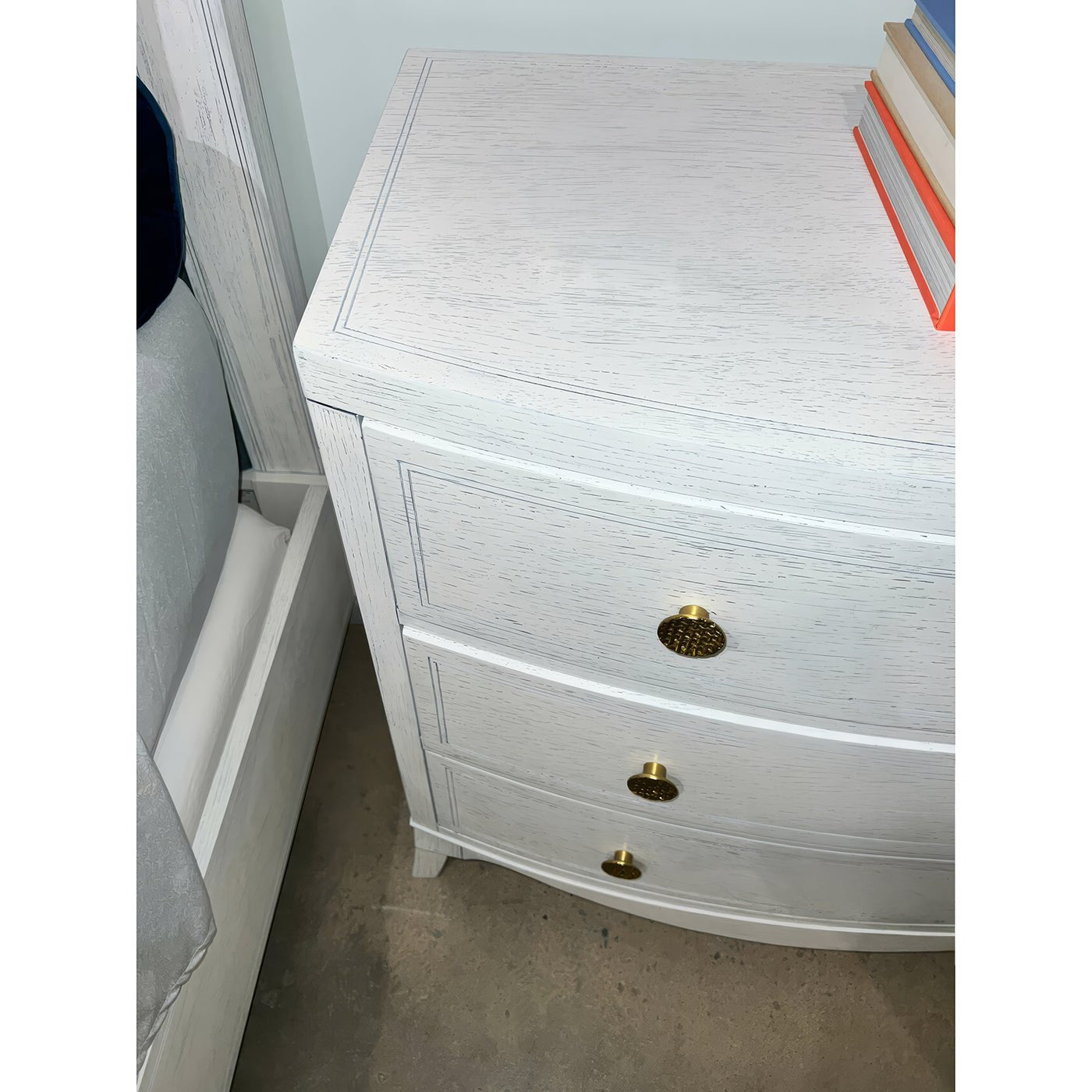 Top-down view of white chest with brass knobs and books.