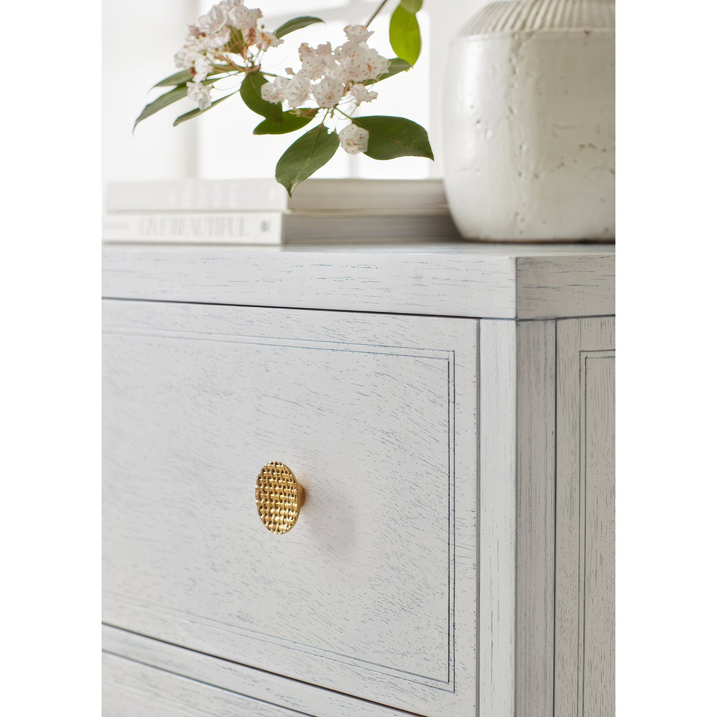 Close-up of white nightstand with decorative knob detail.