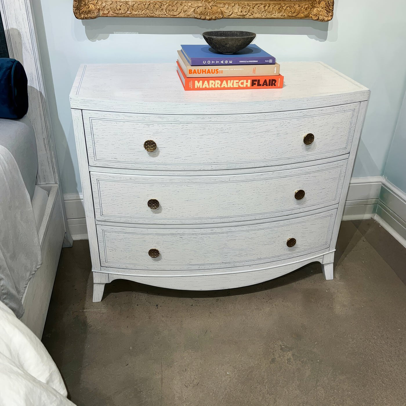 White bedside chest with books and decor items on top.