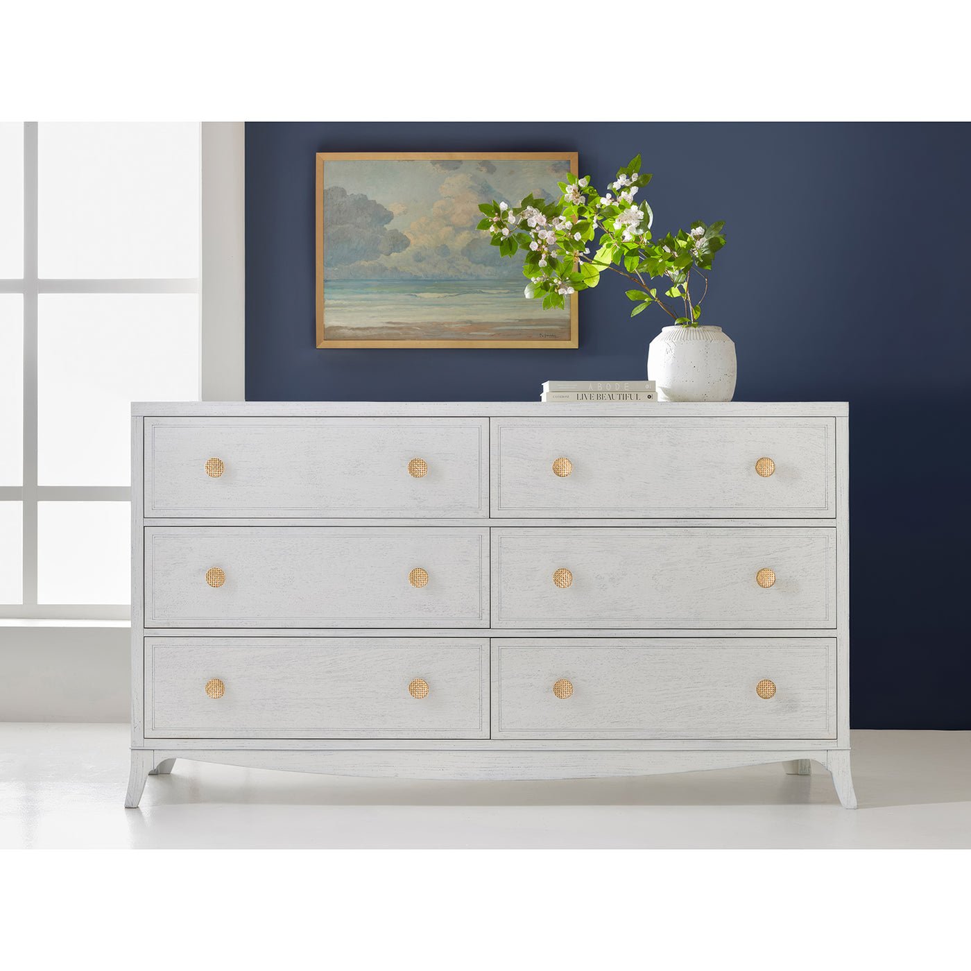 White double dresser styled in room, art and plant.