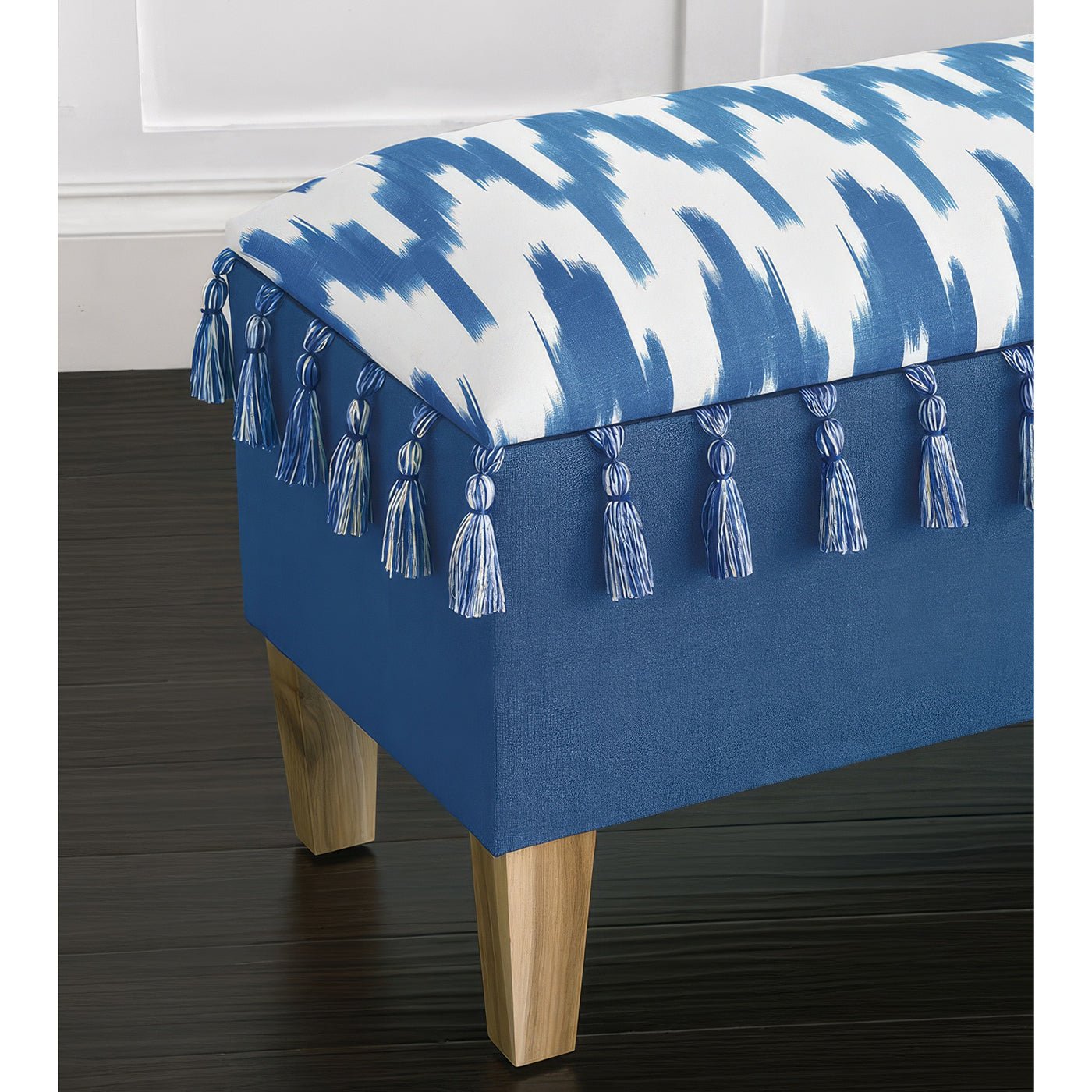 Close-up of tassel and fabric pattern on blue bench.