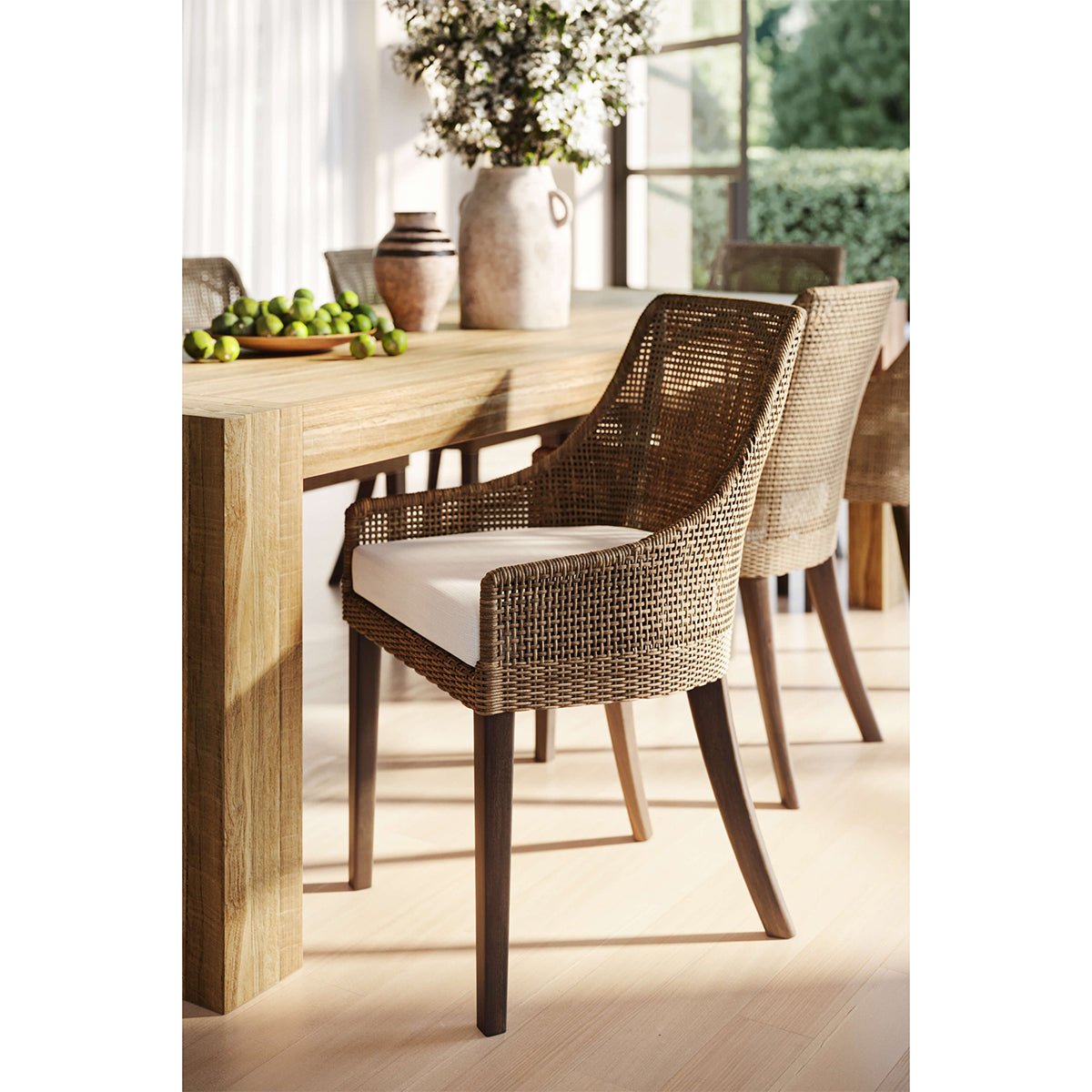 Coastal rattan dining chairs around wooden dining table setting.