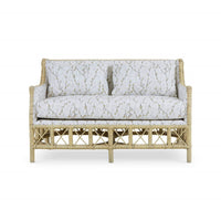 Front view of rattan settee, botanical upholstery visible.