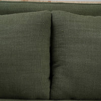 Close-up of green cushions on rattan settee.