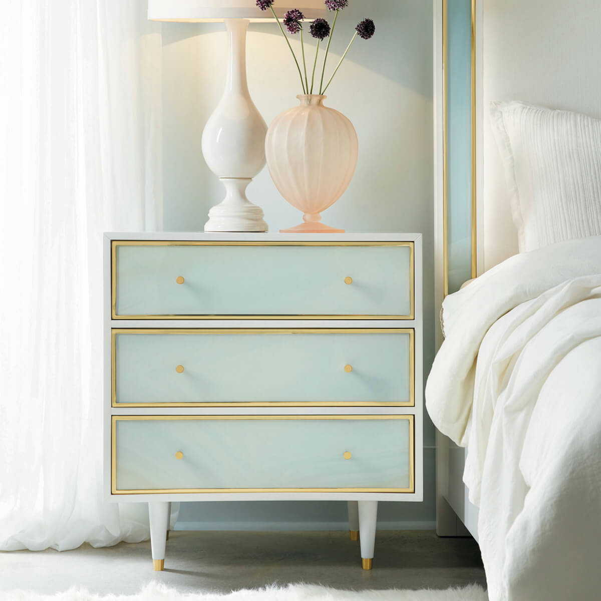 Nightstand next to bed, blue drawers, elegant design.