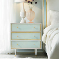 Nightstand next to bed, blue drawers, elegant design.