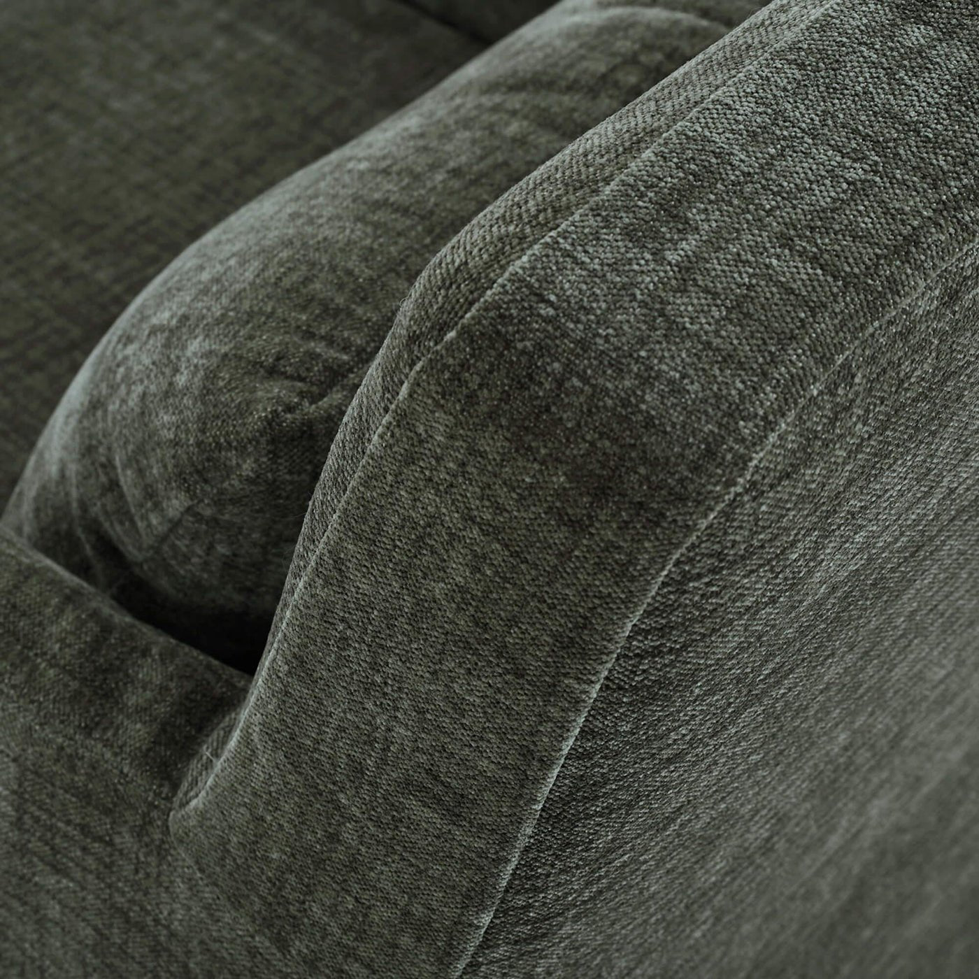 Green slipcovered armchair, close-up of armrest texture.