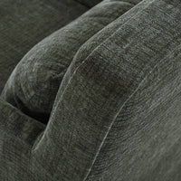 Green slipcovered armchair, close-up of armrest texture.