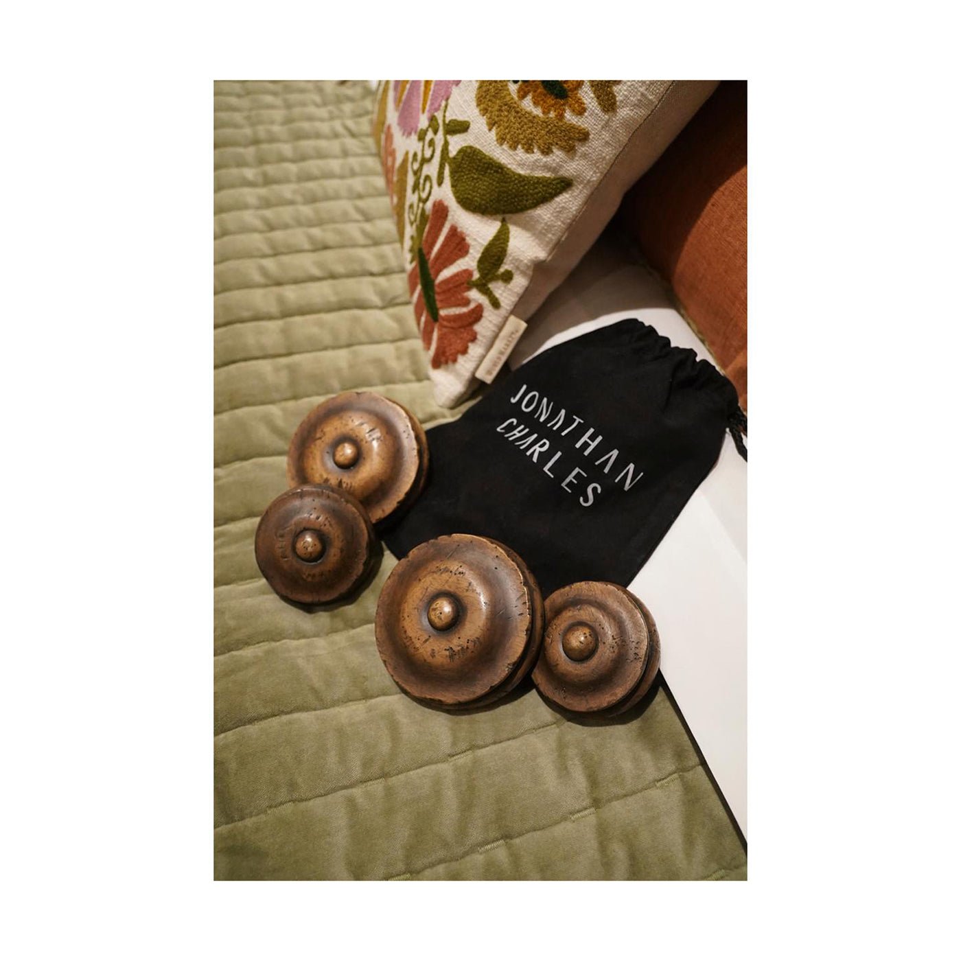 Wooden bed finials displayed with embroidered pillows.