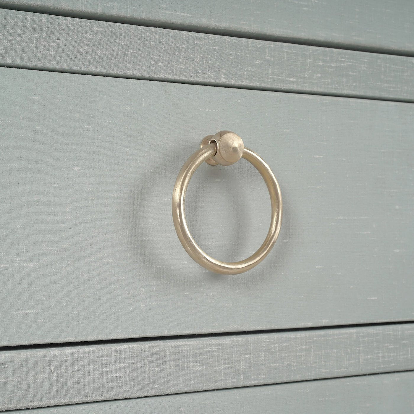 Close-up ring handle on blue linen sideboard drawer.