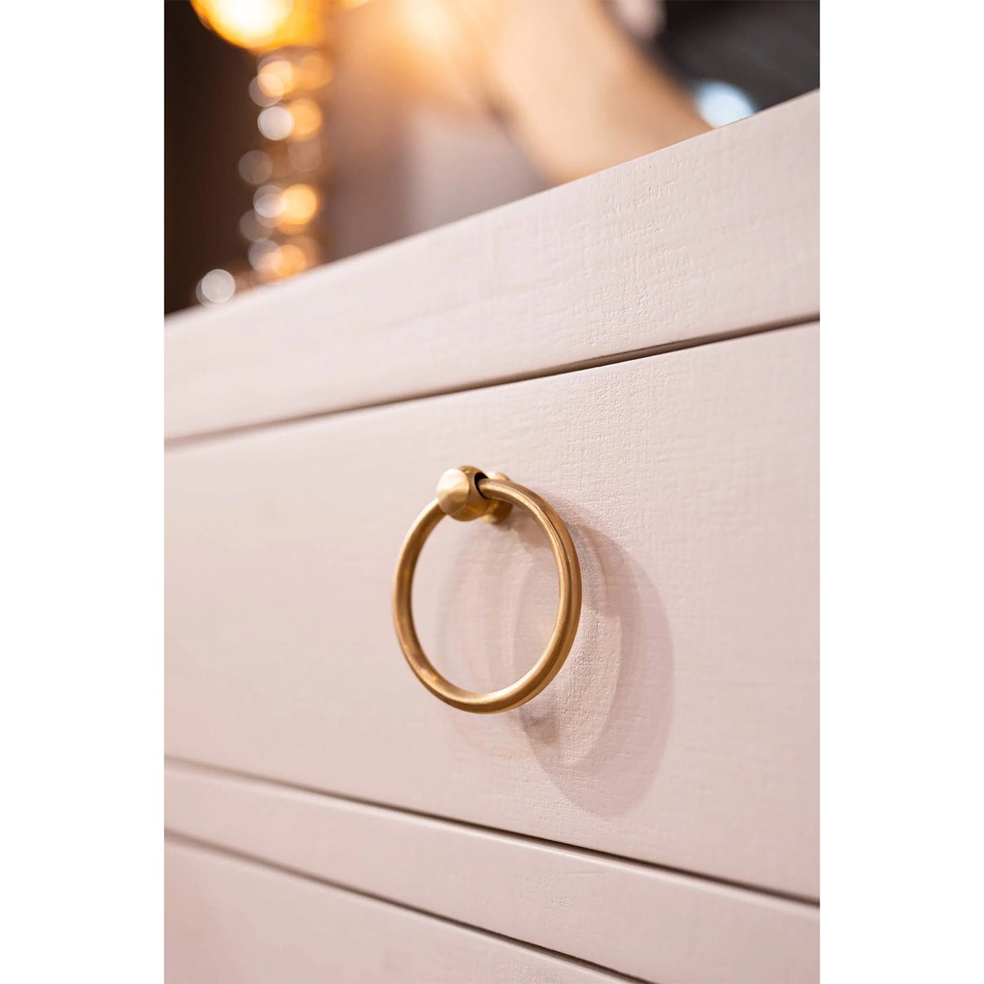 Close-up of sideboard handle, ring design, gold-toned hardware.