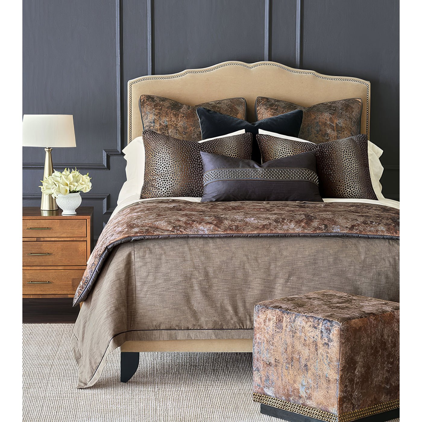 Bedroom scene with copper velvet ottoman in foreground.
