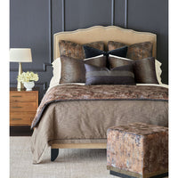 Bedroom scene with copper velvet ottoman in foreground.