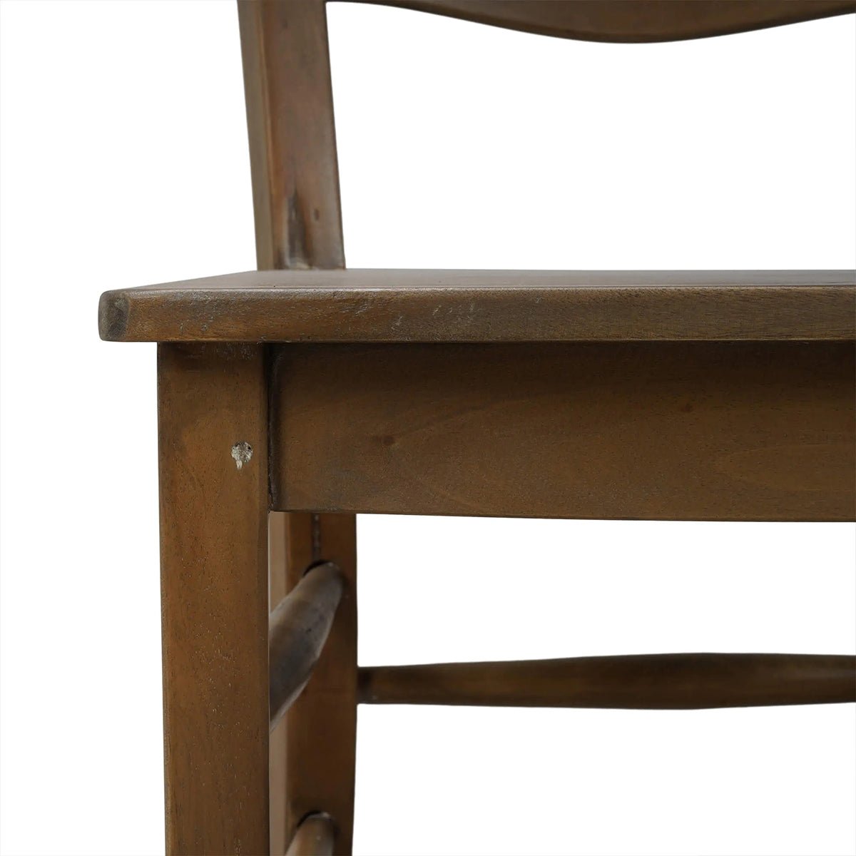 Close-up of wooden ladder back chair's seat edge.