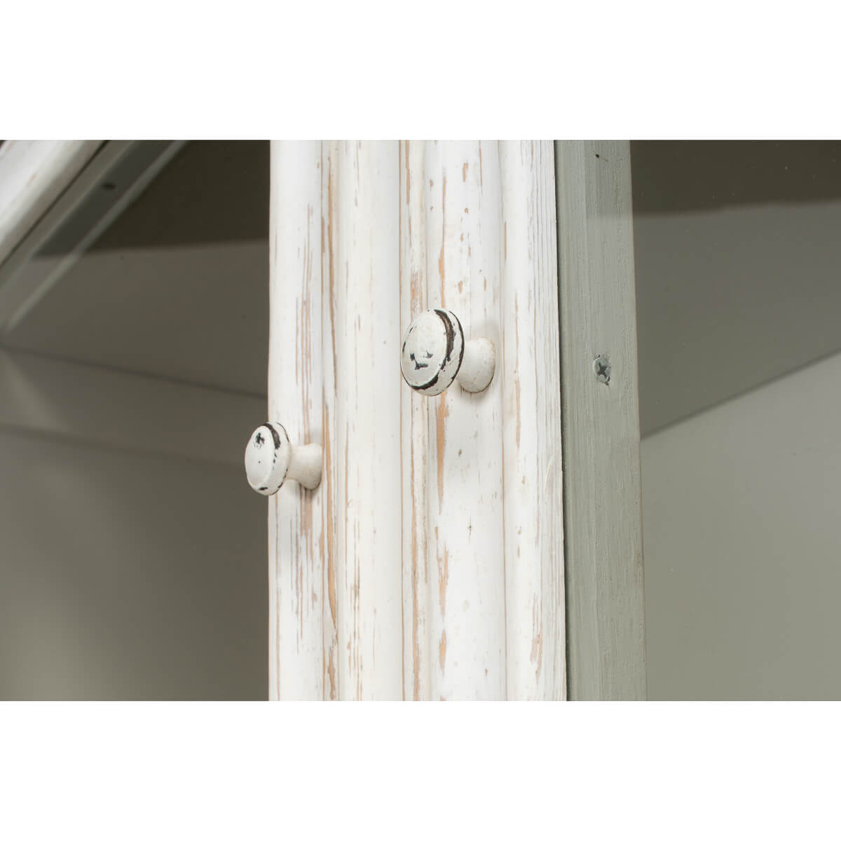 Close-up knobs on display cabinet, distressed white wood.