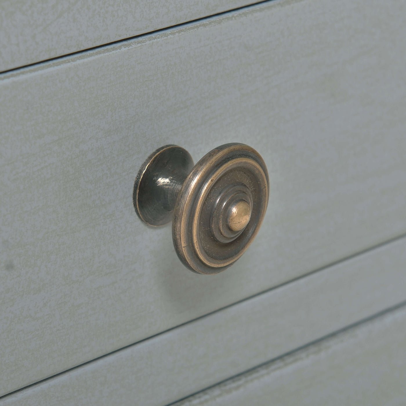 Close-up of round drawer knob on gray side table.