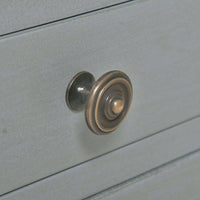 Close-up of round drawer knob on gray side table.
