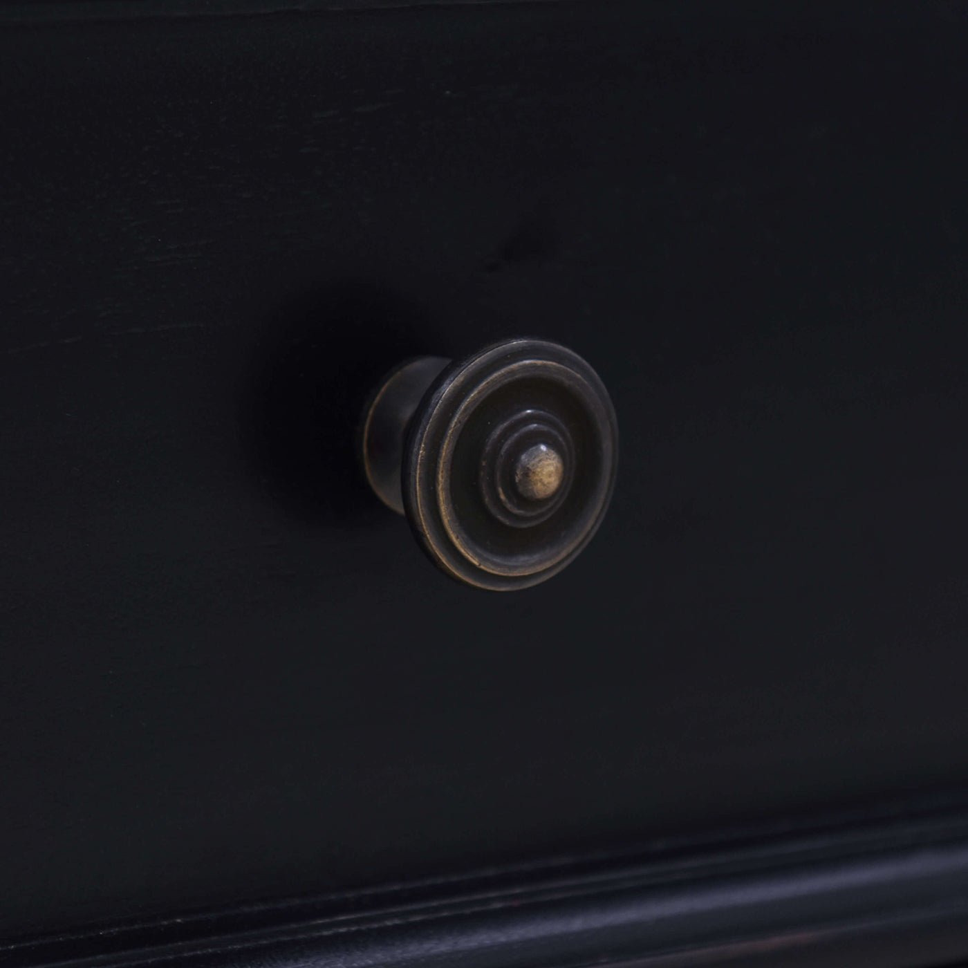 Close-up knob detail on black end table drawer.