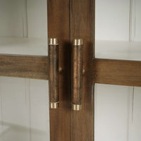 Close-up of sideboard handle on wood and glass door.