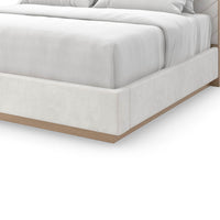 Corner detail of cream upholstered queen bed, wooden base.
