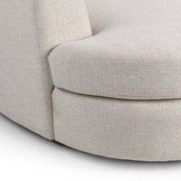 Close-up of ivory bouclé sectional showing the rounded seat edge and upholstered base