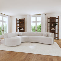 Ivory curved bouclé sectional with round pillows in a bright living room with wood shelving