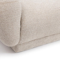 Close-up of cream sectional showing the rounded outer arm, seat edge and upholstered base