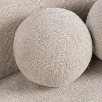 Close-up of a round cream accent pillow against the sectional back