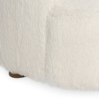 Close-up of cream upholstery wrapping the sectional base above a short round wood foot
