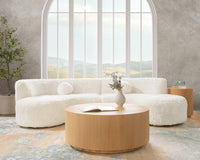 Cream curved sectional styled beneath an arched window with a round wood coffee table
