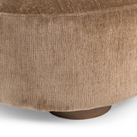 Close-up of brown upholstery around the sectional base above a round wood foot