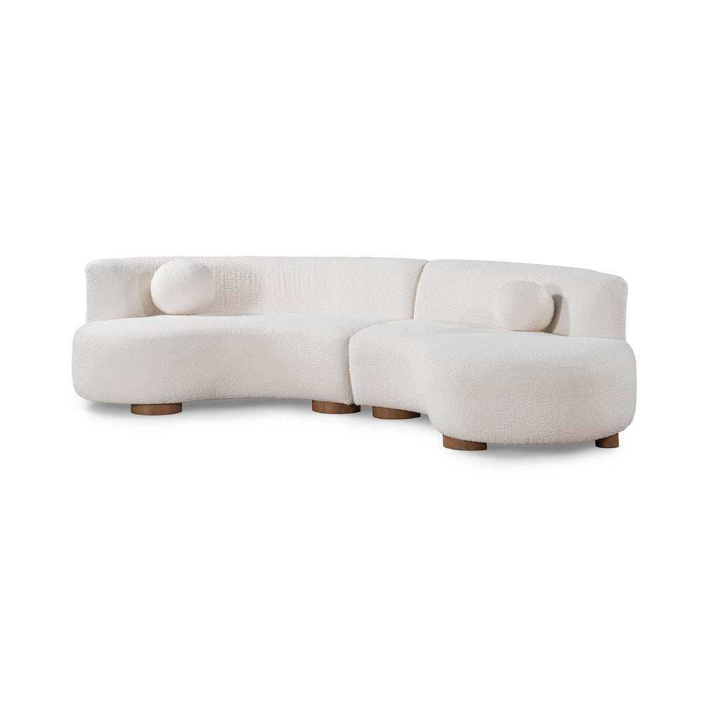 Angled front view of ivory curved sectional showing its rounded seats, low back and round accent pillows
