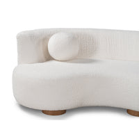 Close-up of ivory sectional seat, curved back and round accent pillow above the wood feet