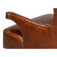 Close-up, arm detail of dark brown leather wing chair.