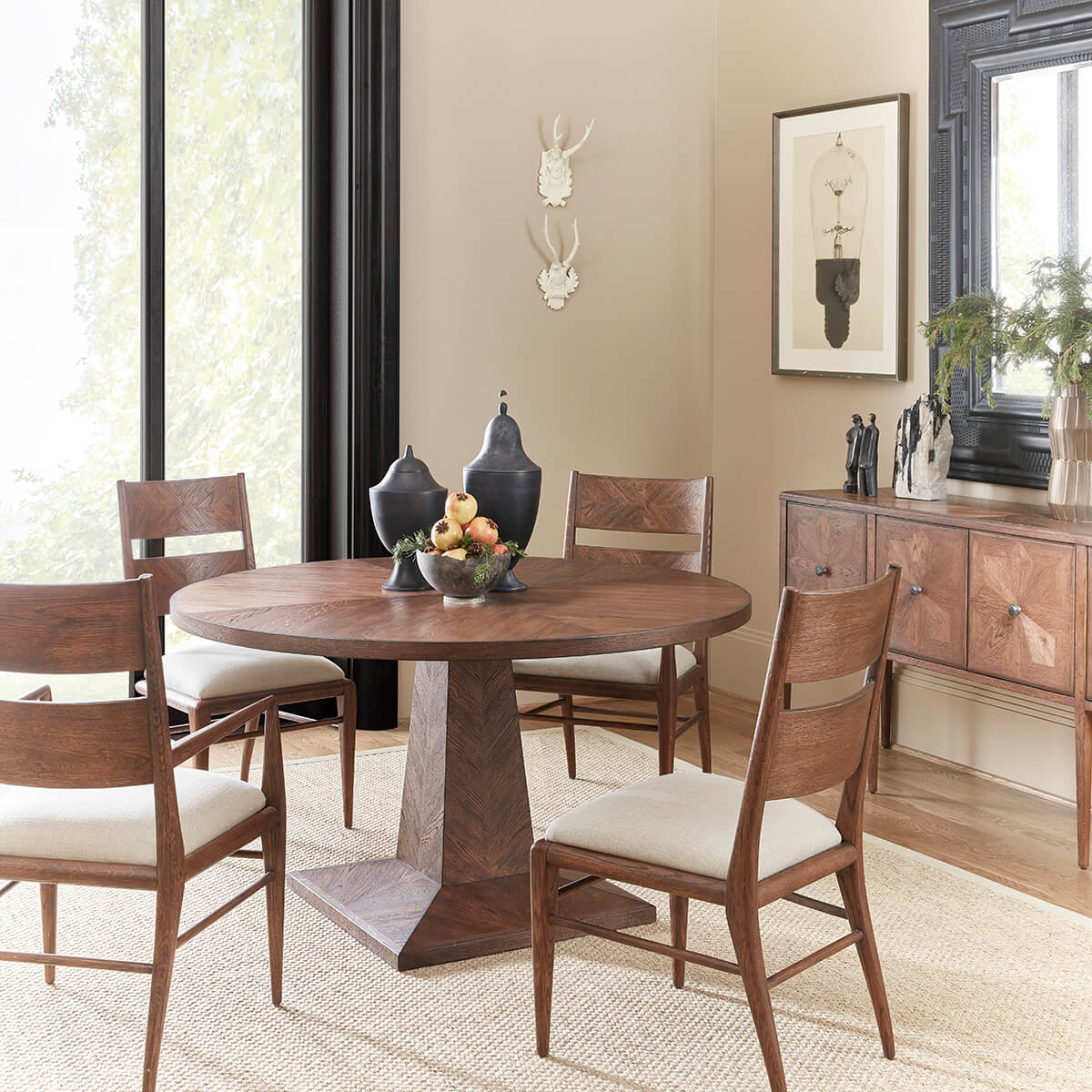 Dining room with round table and four chairs, natural lighting.