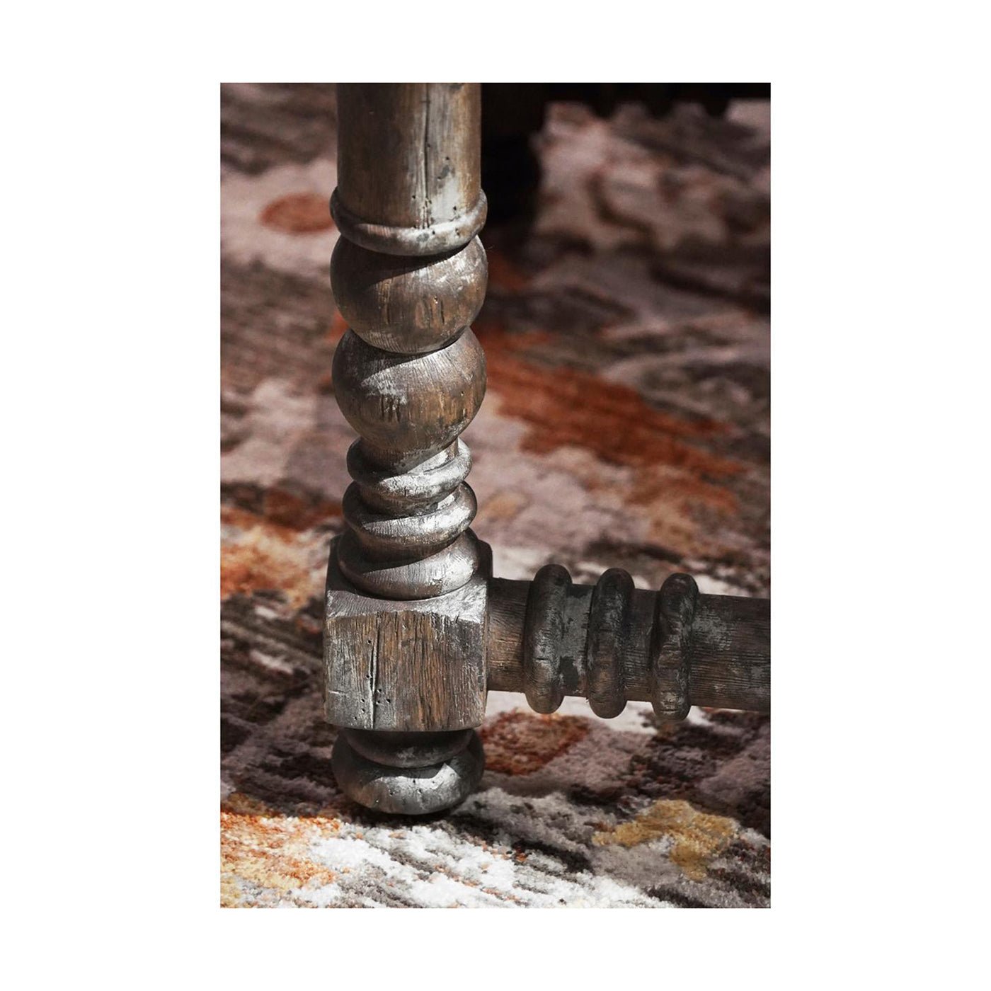Close-up of rustic spool leg on patterned rug.