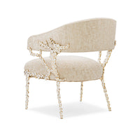 Back angled view of beige modern accent chair, ornate legs.