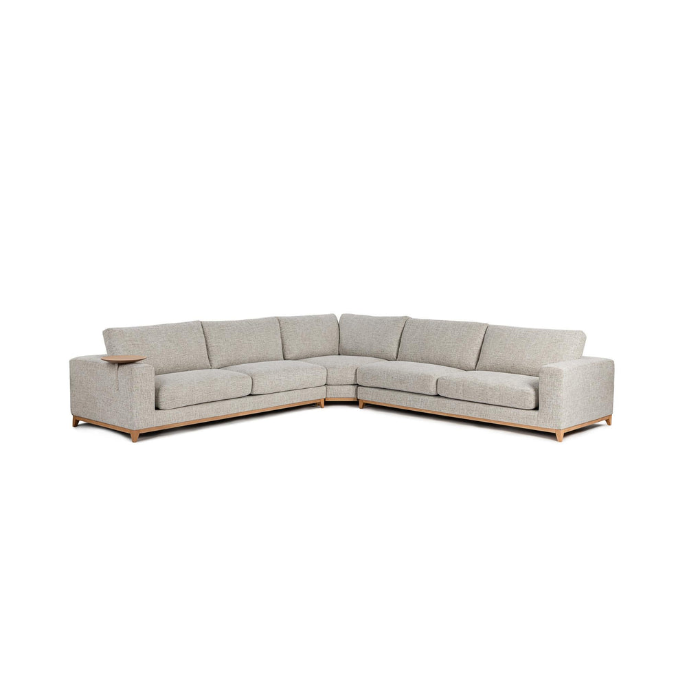 Angled front view of sand three-piece sectional with a wood base and round table at the arm