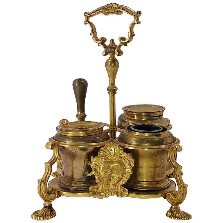 Ornate brass Standish with intricate handle and containers.