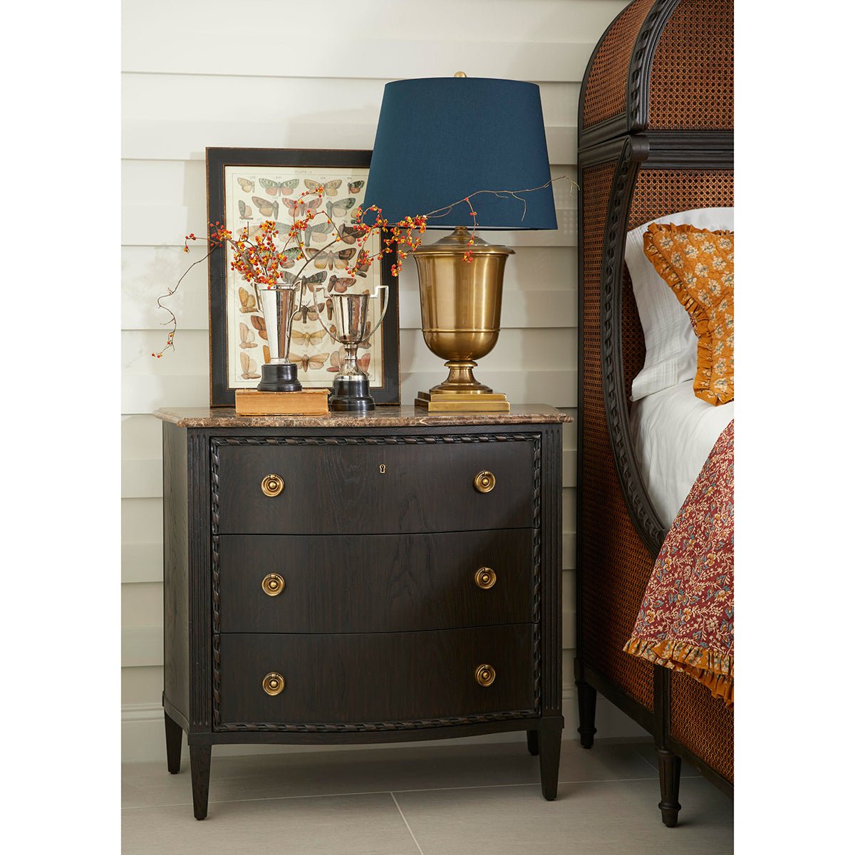 Ebonized marble top chest beside bed with accessories.