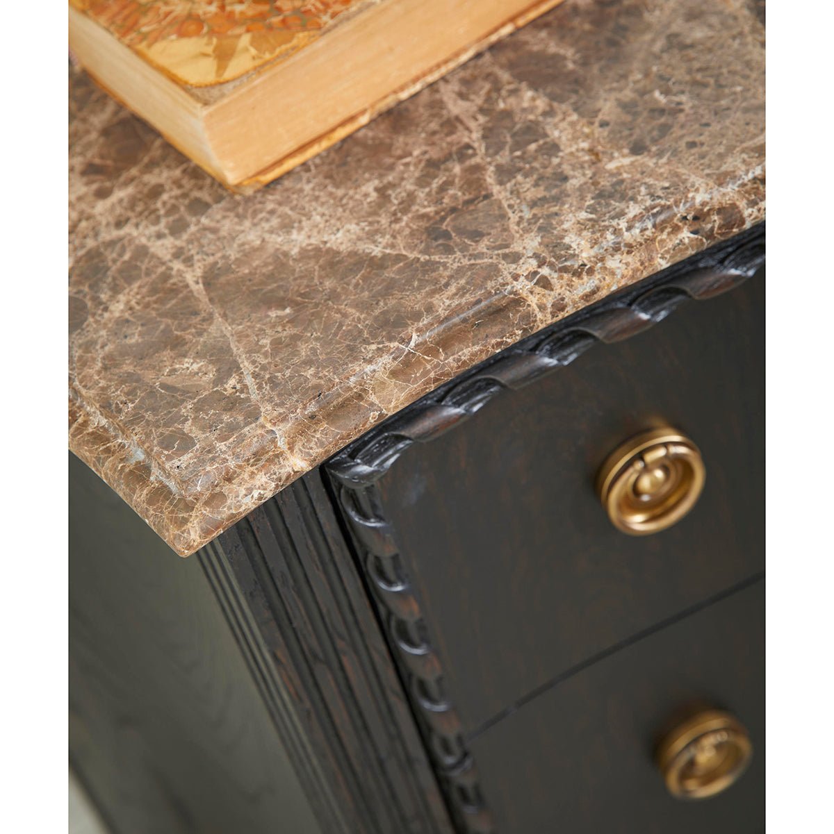Close-up of marble top edge on ebonized chest.