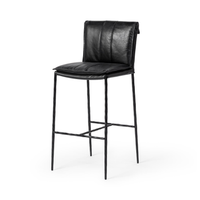 Slim-frame black leather bar stool in a three-quarter front view, showing the stitched seat and slender iron legs
