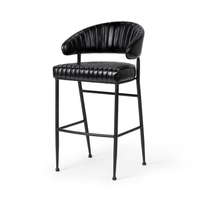 Fluted black leather bar stool in a three-quarter front view, showing the curved back and iron footrest