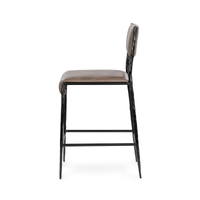 Side view of the taupe leather counter stool showing its slim iron frame and tapered legs