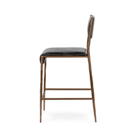 Side view of the black leather counter stool showing tapered iron legs and the slim seat profile