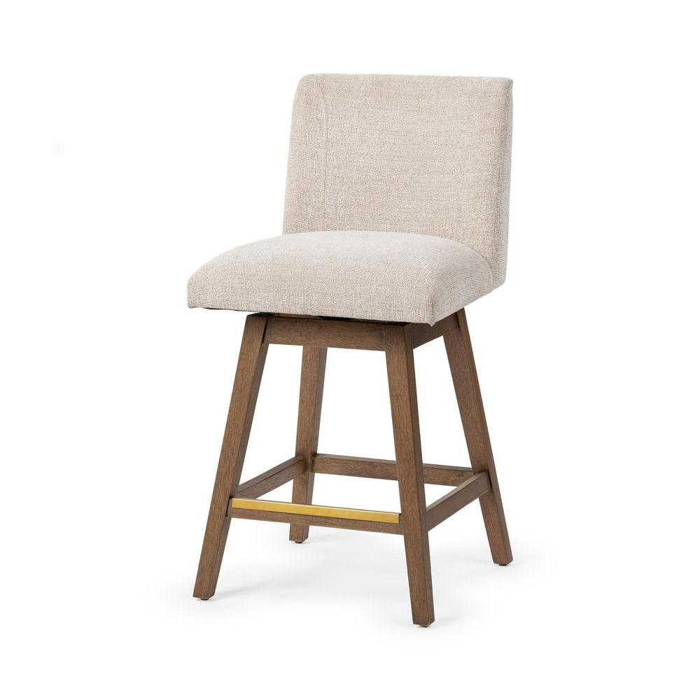 Three-quarter front view of a cream fabric swivel counter stool with brown wood legs and a brass-toned footrest