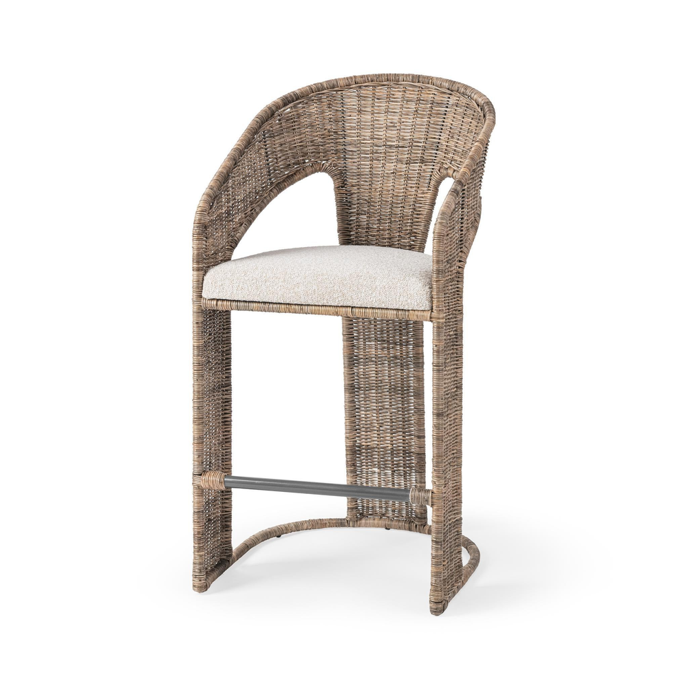 Three-quarter front view of a natural rattan counter stool with open arms and a cream seat cushion