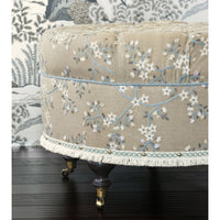 Side view of embroidered poof, black wooden floor.