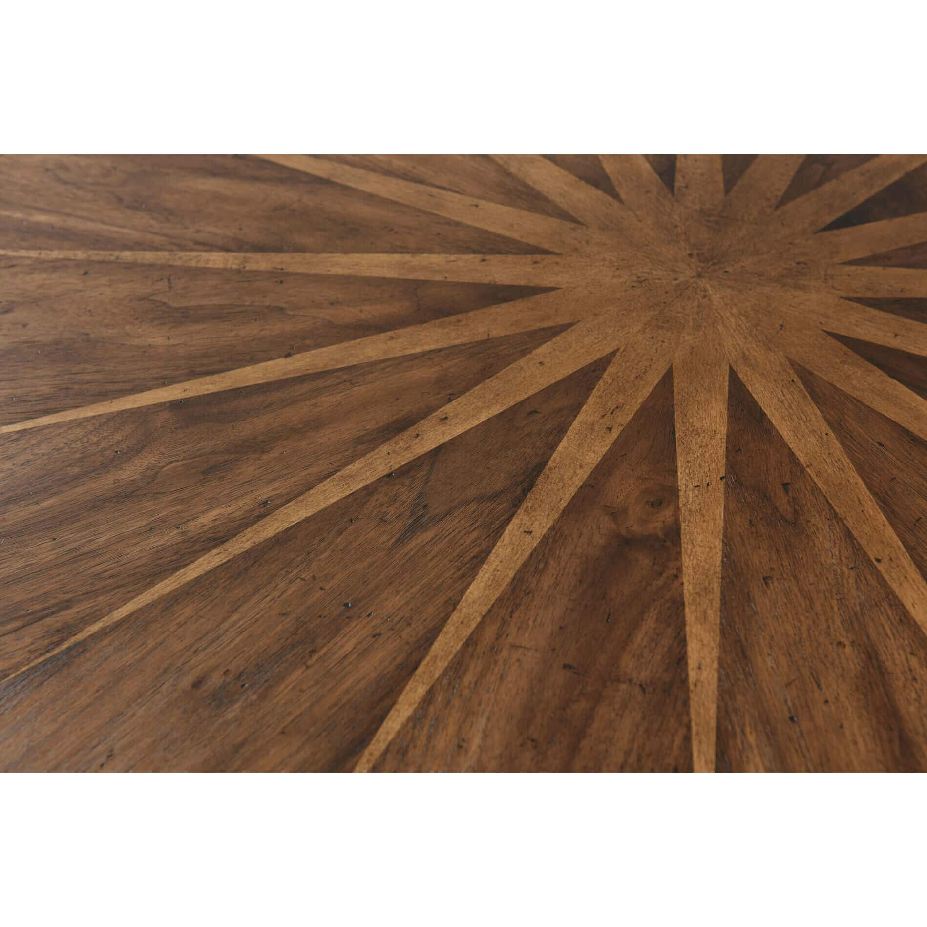 Starburst pattern detail on wooden dining table top.